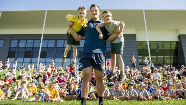 Brumbies giant Tyrel Lomax lifts up Lachlan, 7, and Nicolas, 8, at the Budding Brumbies school clinics. Photo: Jay Cronan