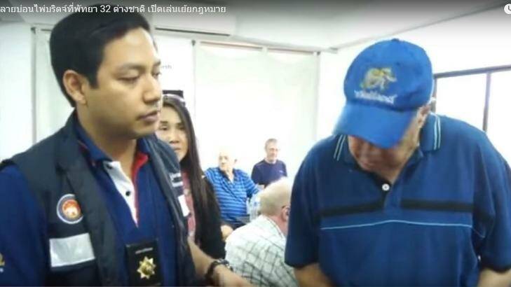 An elderly bridge player is questioned by a Thai policeman at a Jomtien & Pattaya Bridge Club meeting in Pattaya. Photo: Youtube