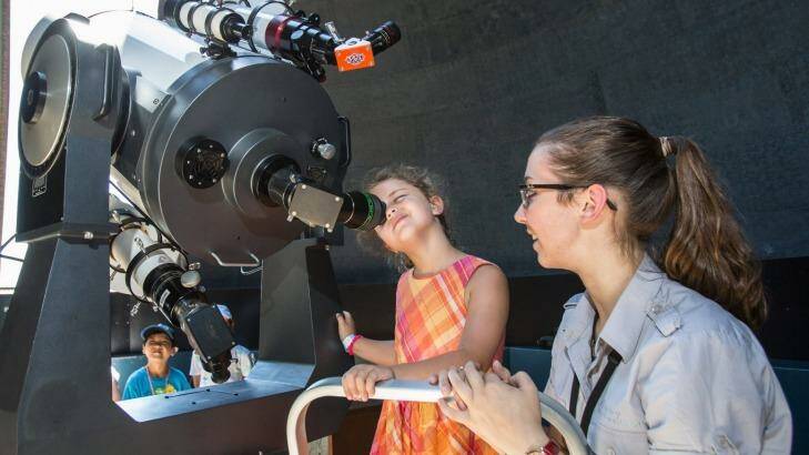 Aboriginal astronomy tour guide Kirsten Banks assists Tia, 6, at the Sydney Observatory this year. Photo: Cole Bennetts
